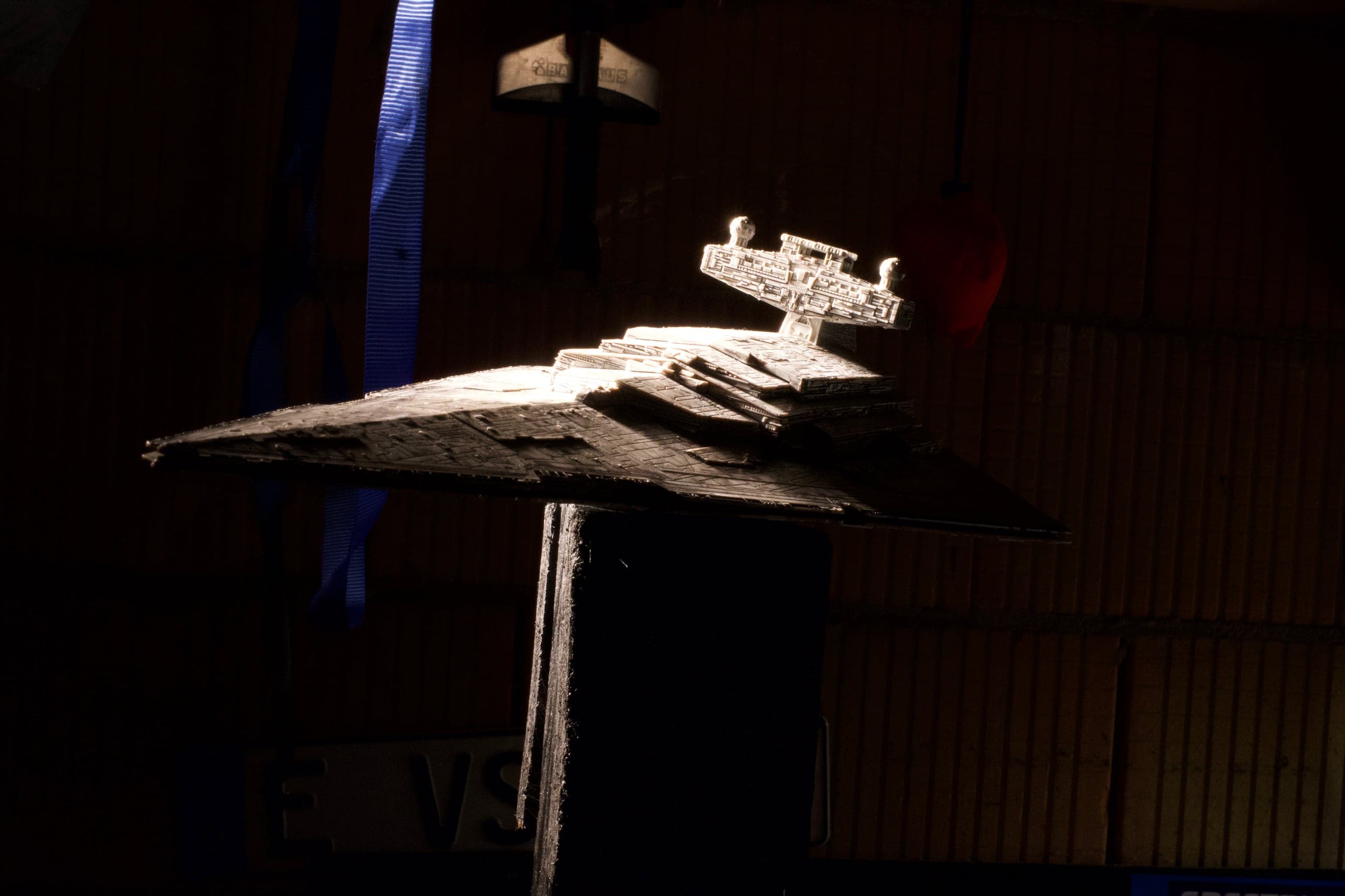 The full starship miniature under a single hard key light in the workshop