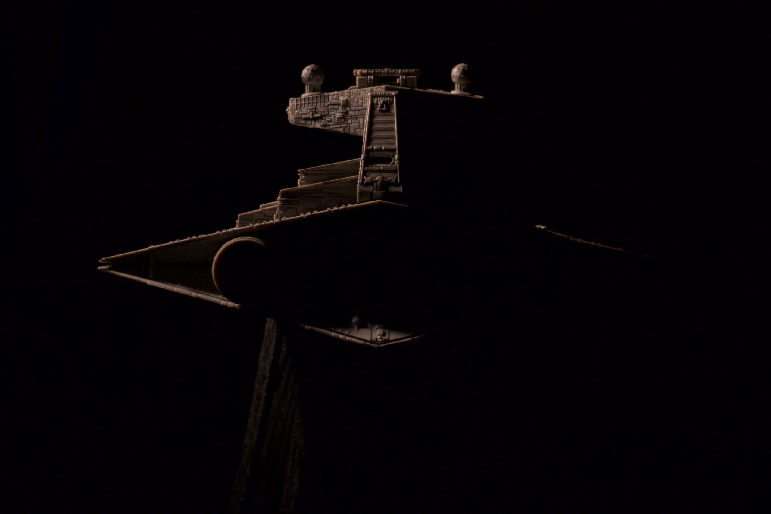 Studio-scale starship miniature lit with a single hard key light against black